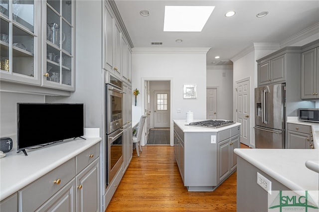 kitchen with stainless steel appliances, a center island, gray cabinets, and visible vents