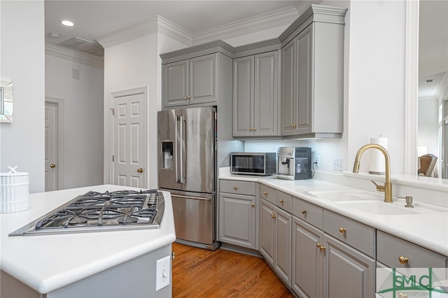 kitchen featuring gray cabinetry, ornamental molding, a sink, light wood-type flooring, and stainless steel fridge