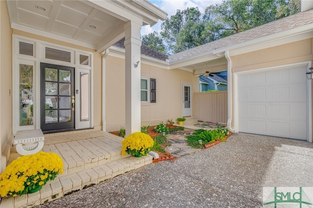 entrance to property featuring roof with shingles, an attached garage, and stucco siding