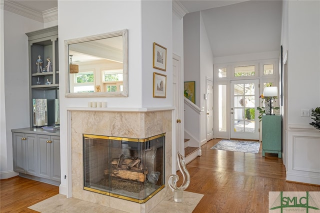 living room featuring ornamental molding, plenty of natural light, a tile fireplace, and light hardwood / wood-style flooring