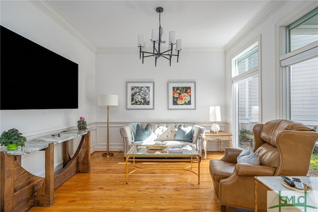 living room featuring light wood-type flooring, a notable chandelier, and ornamental molding