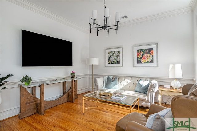 living room featuring ornamental molding, a chandelier, and light hardwood / wood-style floors