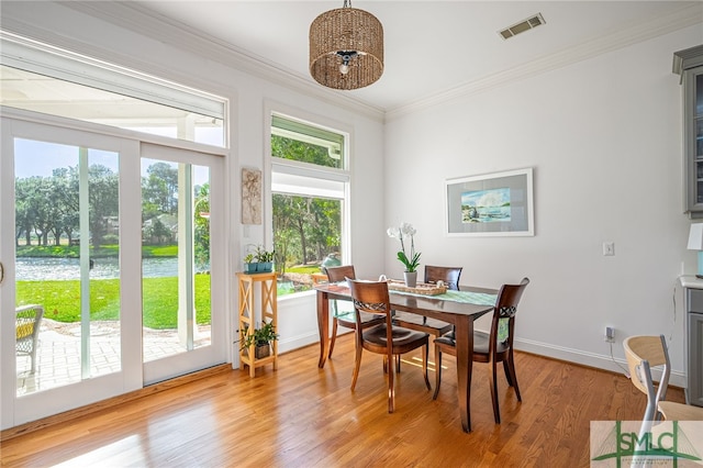 dining space featuring ornamental molding and light hardwood / wood-style flooring