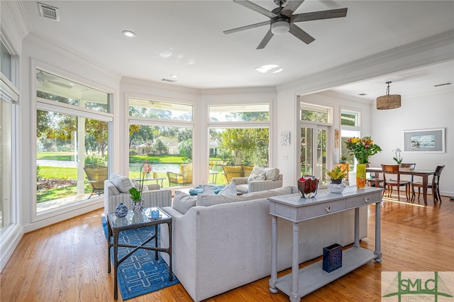 living room featuring crown molding, light hardwood / wood-style floors, and plenty of natural light