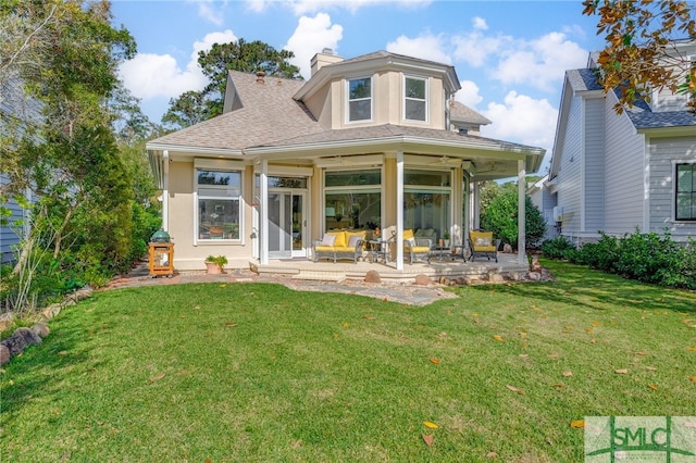 back of property with a chimney, roof with shingles, a yard, a patio area, and an outdoor living space