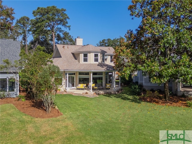 rear view of house with a lawn, a chimney, and a patio