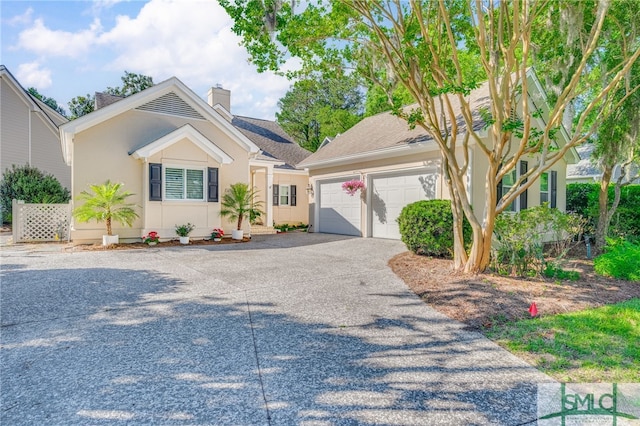 view of front of house with asphalt driveway, a garage, stucco siding, and a chimney