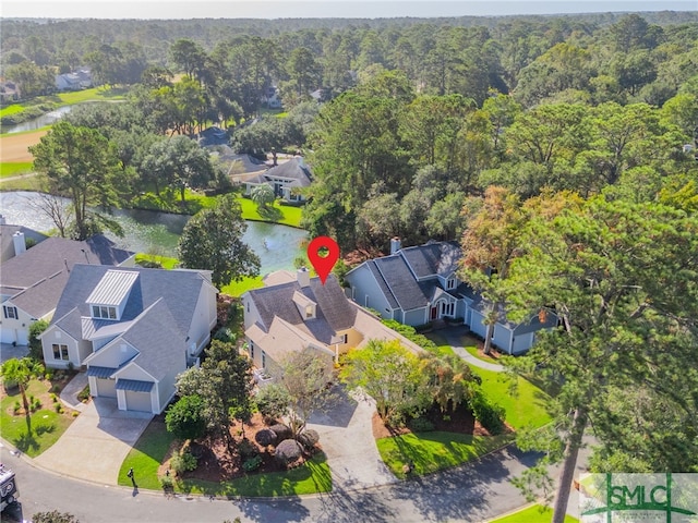 aerial perspective of suburban area featuring a forest and a nearby body of water