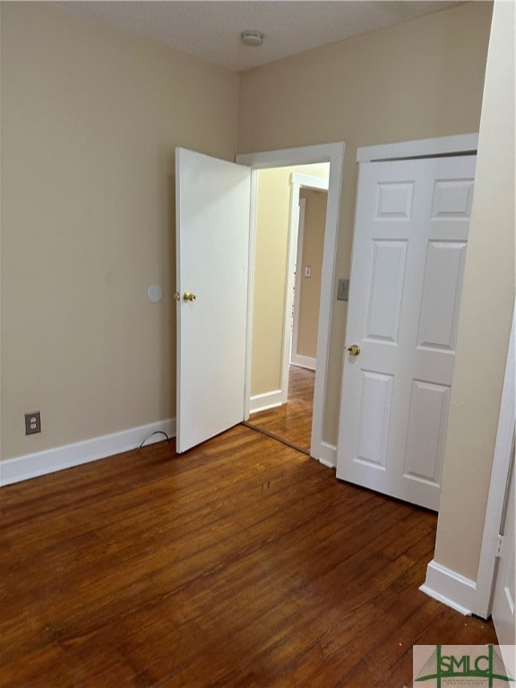 unfurnished bedroom with dark wood-type flooring and a closet