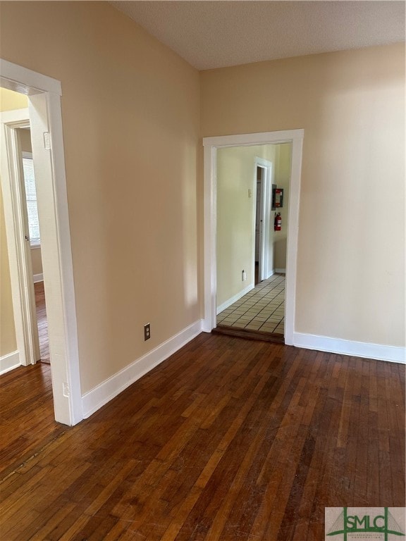 spare room featuring dark wood-type flooring and a textured ceiling