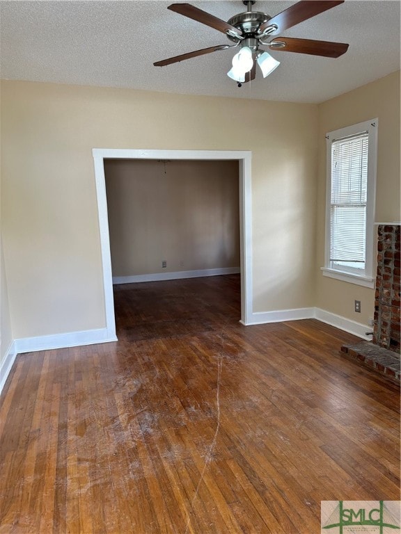 unfurnished living room featuring dark wood-type flooring, a textured ceiling, and ceiling fan