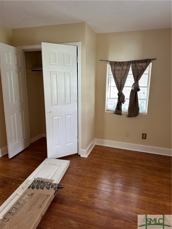 unfurnished bedroom featuring dark hardwood / wood-style floors, a textured ceiling, and a closet