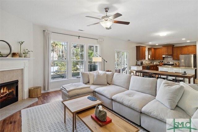 living room with ceiling fan, light hardwood / wood-style floors, and a fireplace