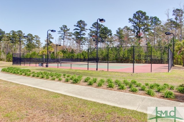 view of tennis court featuring a lawn