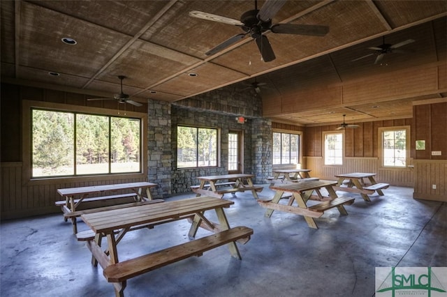 misc room with concrete flooring, plenty of natural light, and wooden walls