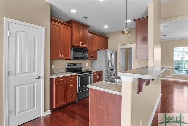 kitchen with stainless steel appliances, kitchen peninsula, a kitchen bar, decorative light fixtures, and dark hardwood / wood-style flooring