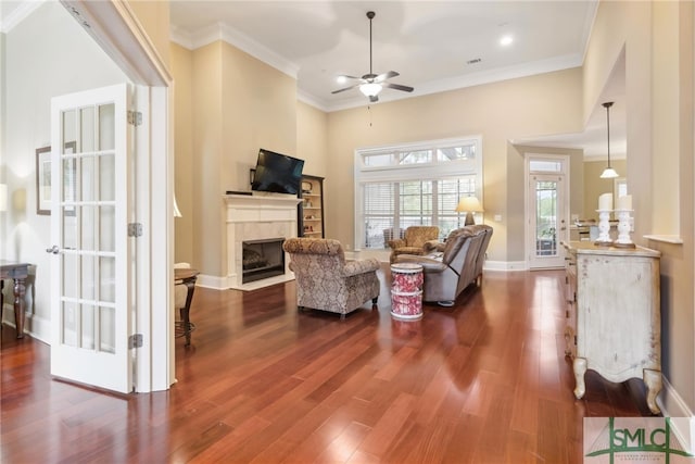 living room with hardwood / wood-style floors, ceiling fan, ornamental molding, and a tiled fireplace