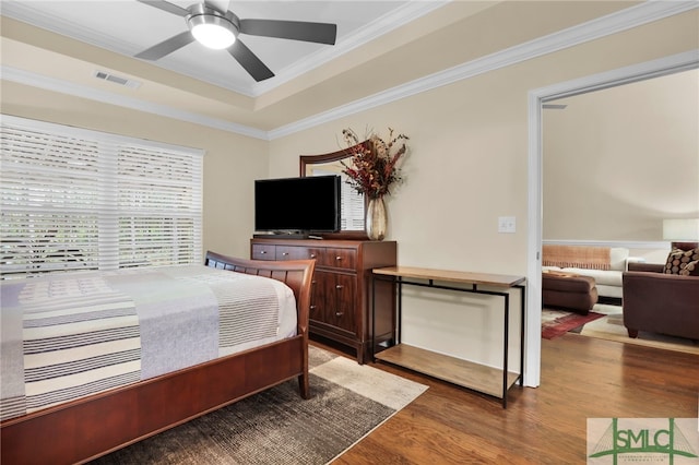 bedroom featuring ornamental molding, hardwood / wood-style floors, ceiling fan, and a tray ceiling