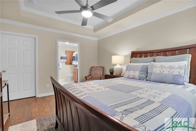 bedroom with ensuite bath, wood-type flooring, ornamental molding, ceiling fan, and a raised ceiling