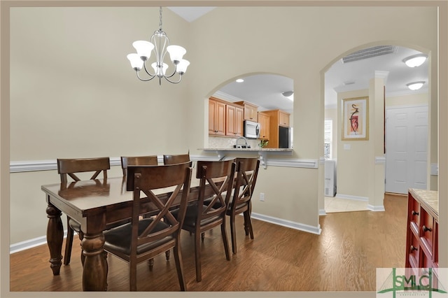 dining room featuring light wood-type flooring, an inviting chandelier, and ornamental molding