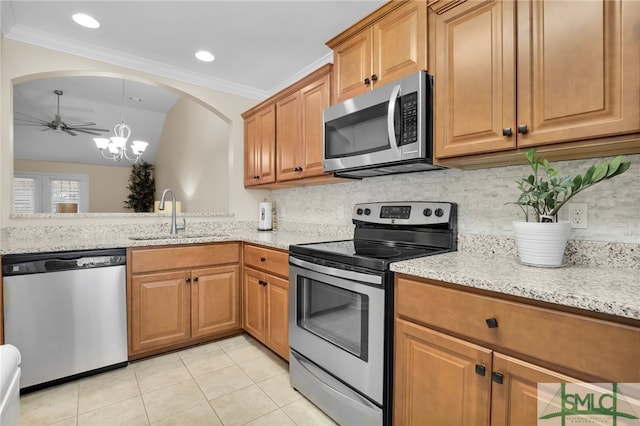 kitchen with light stone counters, appliances with stainless steel finishes, light tile patterned floors, decorative backsplash, and sink