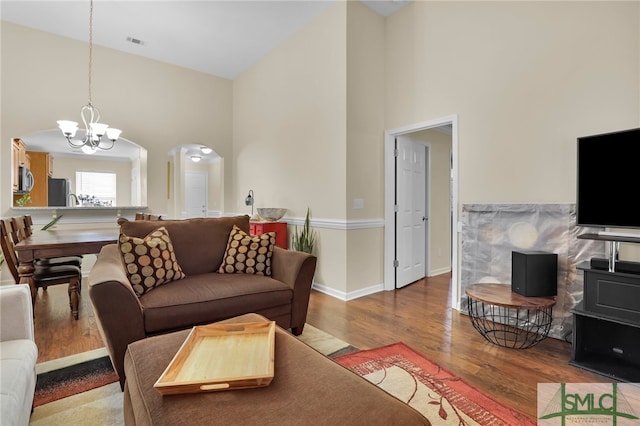 living room with a high ceiling, a chandelier, and wood-type flooring