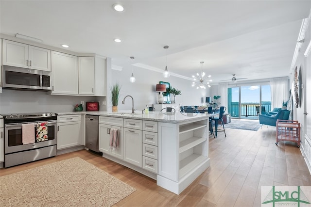 kitchen featuring stainless steel appliances, sink, kitchen peninsula, ornamental molding, and white cabinets