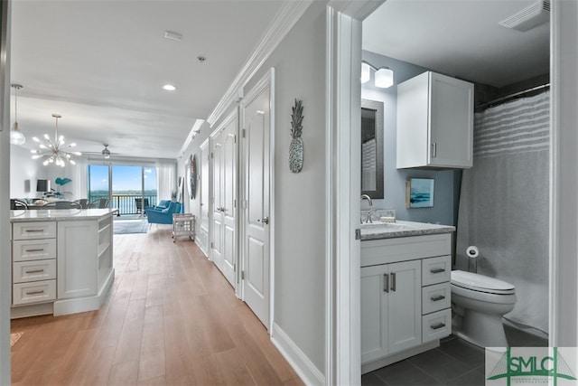 bathroom with an inviting chandelier, vanity, wood-type flooring, toilet, and walk in shower