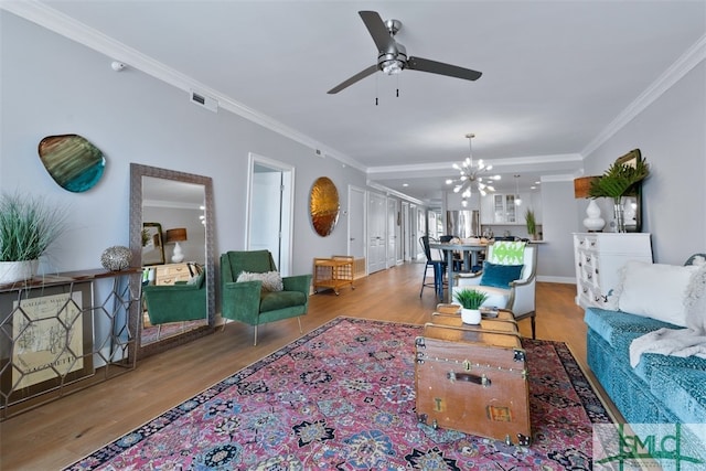 living room with crown molding, ceiling fan with notable chandelier, and light wood-type flooring