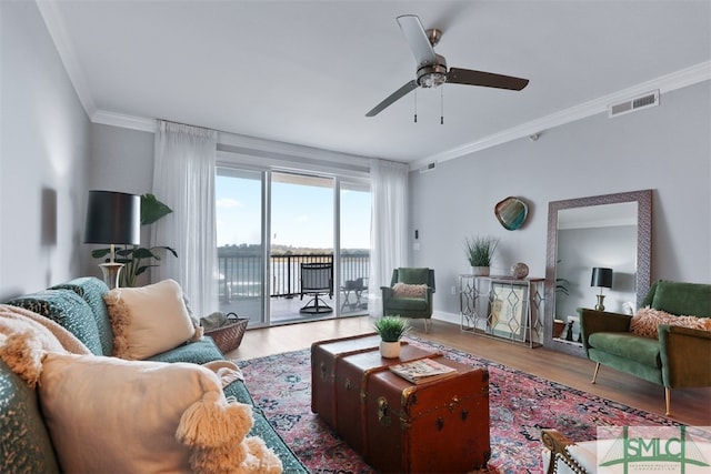 living room with crown molding, light wood-type flooring, ceiling fan, and a water view