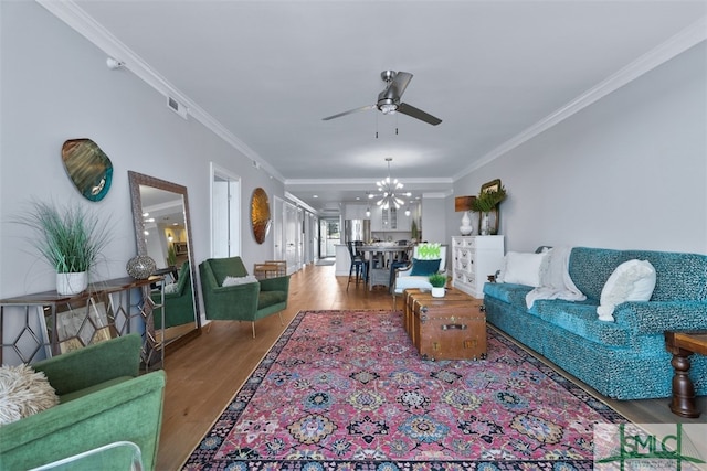 living room featuring hardwood / wood-style floors, ceiling fan with notable chandelier, and ornamental molding