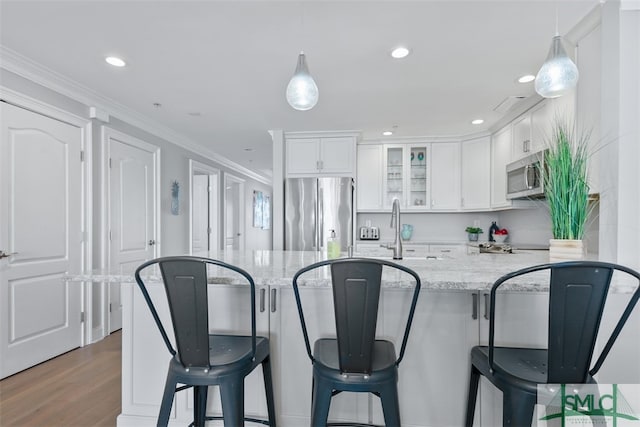 kitchen with decorative light fixtures, a breakfast bar area, white cabinets, light stone counters, and stainless steel appliances