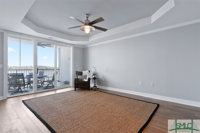 unfurnished room featuring a water view, ceiling fan, a raised ceiling, and hardwood / wood-style flooring