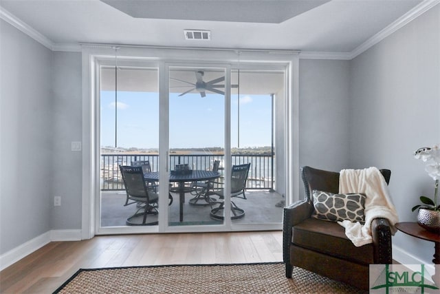 interior space with a water view, ceiling fan, crown molding, and hardwood / wood-style flooring