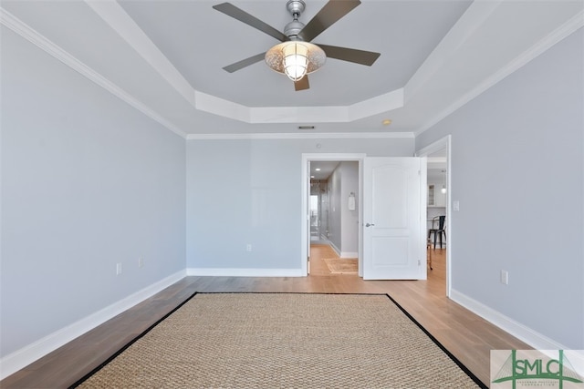 unfurnished bedroom featuring a tray ceiling, ornamental molding, and light wood-type flooring