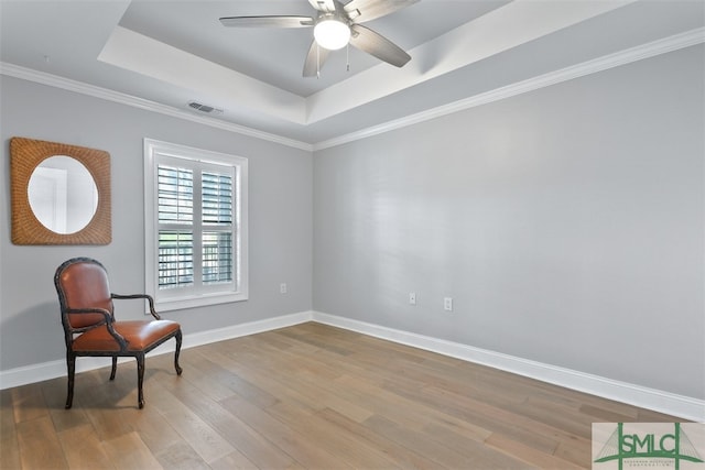 sitting room featuring crown molding, ceiling fan, a tray ceiling, and light hardwood / wood-style flooring