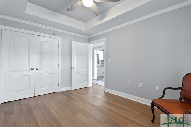 unfurnished room with a tray ceiling, ceiling fan, and light wood-type flooring