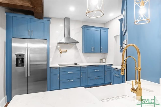 kitchen with wall chimney exhaust hood, black electric cooktop, decorative light fixtures, and stainless steel fridge