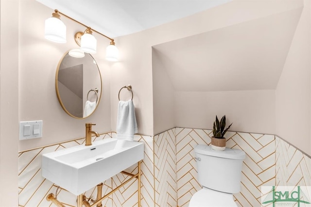 bathroom with toilet, tile walls, sink, and lofted ceiling