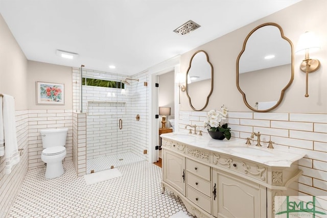 bathroom featuring tile patterned floors, toilet, tile walls, an enclosed shower, and vanity