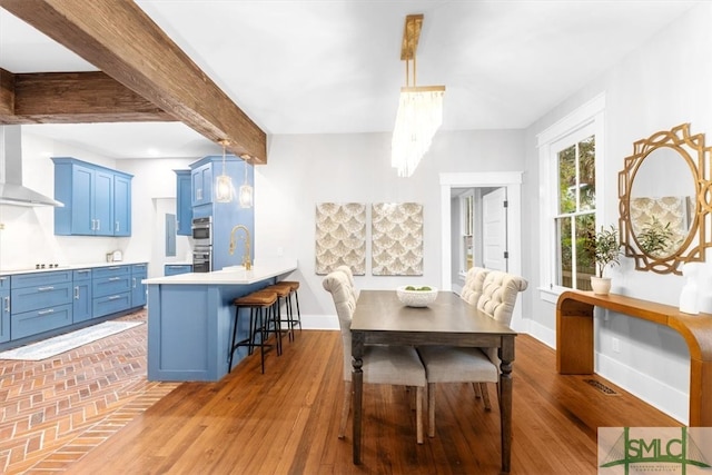 dining area featuring hardwood / wood-style flooring, beam ceiling, and a notable chandelier