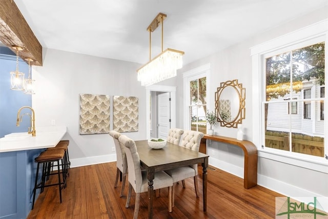 dining room with dark wood-type flooring, sink, and an inviting chandelier