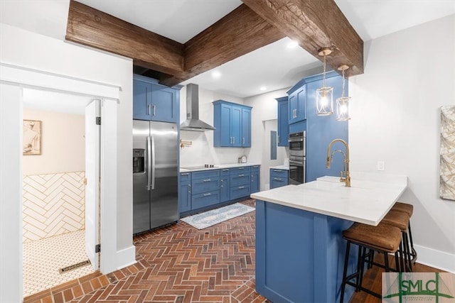 kitchen featuring blue cabinets, kitchen peninsula, wall chimney exhaust hood, a breakfast bar, and appliances with stainless steel finishes