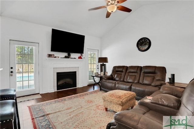 living room with a tiled fireplace, vaulted ceiling, hardwood / wood-style flooring, and ceiling fan