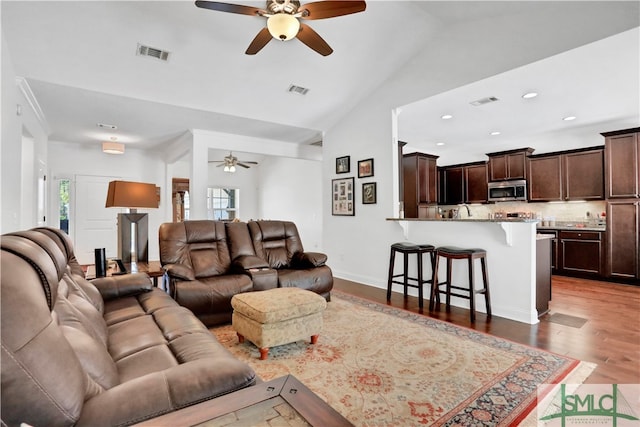 living room with light wood-type flooring, plenty of natural light, lofted ceiling, and ceiling fan