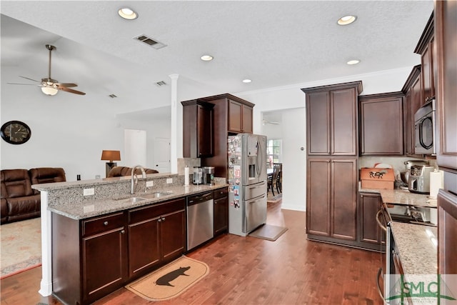 kitchen with appliances with stainless steel finishes, a textured ceiling, sink, dark wood-type flooring, and kitchen peninsula