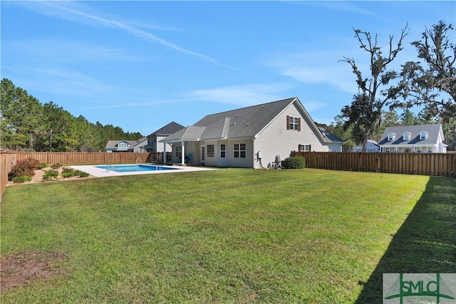 back of property featuring a yard and a fenced in pool