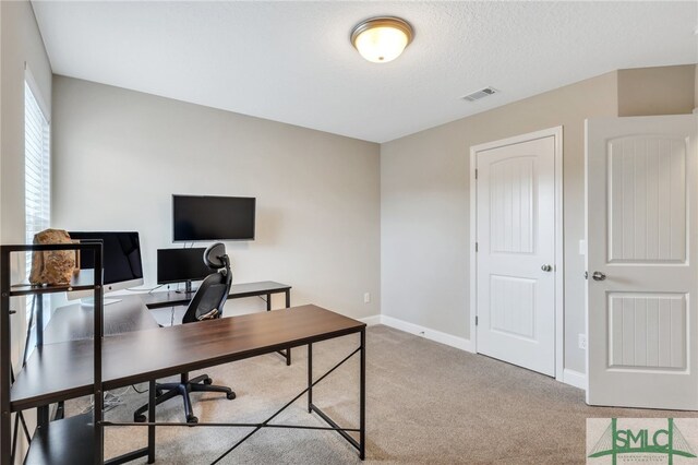 carpeted office space featuring a textured ceiling