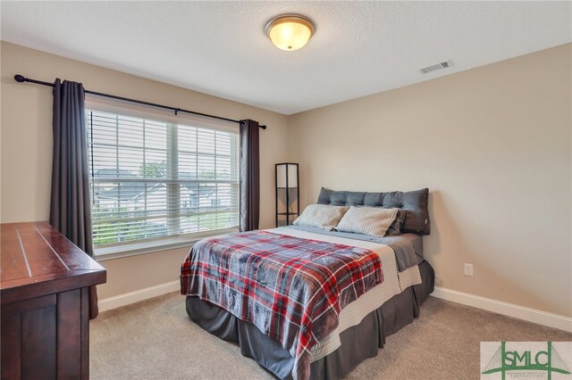 bedroom with a textured ceiling and light carpet