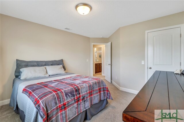 bedroom featuring connected bathroom and light carpet